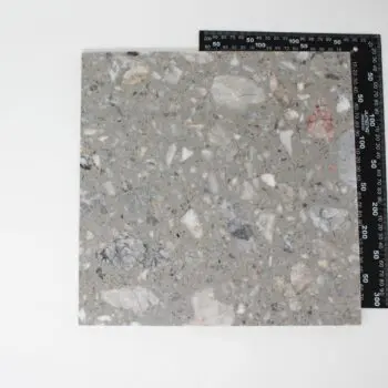 The CG003 tile is a square terrazzo piece featuring grey and white stone chips, displayed on a white background with a black ruler highlighting its dimensions.