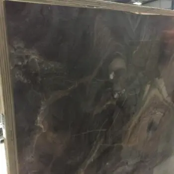 A large, polished slab of ONX004 - Onice Viola, featuring dark brown and black swirling natural patterns, stands vertically in an industrial storage area.